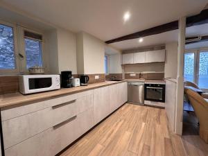 a kitchen with white cabinets and a microwave at Murat - La maison de la petite place in Murat