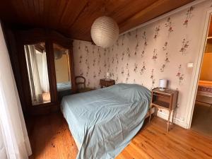 a bedroom with a bed and a table with a mirror at Murat - La maison de la petite place in Murat