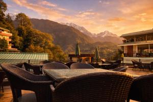 a restaurant with tables and chairs with mountains in the background at AH Grand Villa - Hotel Near Dalai Lama Temple in McLeod Ganj