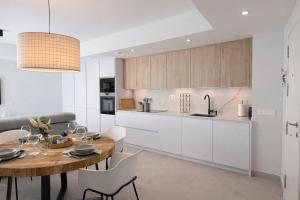 a kitchen with a wooden table and white cabinets at NUEVO-LUZ DE CONIL piscina y parking in Conil de la Frontera