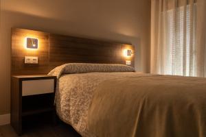 a bedroom with a large bed with a wooden headboard at Hostal Los Rosales in Tejeda de Tiétar