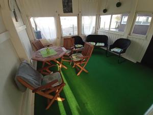 a room with a table and chairs and green carpet at Plázs Vendégházak 1 ,2 in Tiszafüred