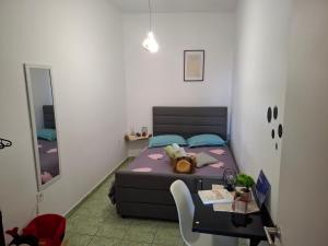 ein kleines Schlafzimmer mit einem Bett, einem Tisch und einem Spiegel in der Unterkunft Le Rocher 2 in Ermoupoli