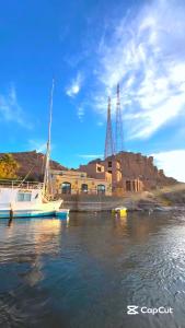 a boat sitting in the water in front of a building at Shellaly Ca Nubian Heritage House in Jazīrat Salūjah