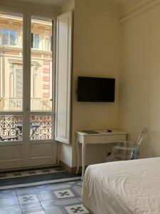 a bedroom with a bed and a television and a window at XX SETTEMBRE Urban Relais in Turin