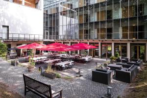 a patio with tables and red umbrellas in front of a building at Ringhotel Schorfheide I Waldresort Werbellinsee in Joachimsthal
