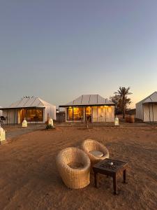 a building in the middle of a field with a table at Peaceful Luxury Camp in Merzouga
