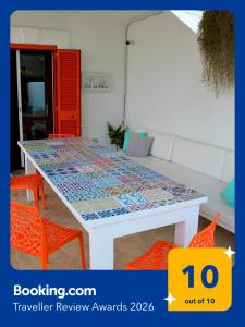 ein Tisch mit orangefarbenen Stühlen und einer Mosaik-Tischplatte in der Unterkunft EcoLiving Casa Vacanze in Torre Lapillo + 174 Fotos