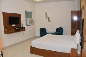 a bedroom with a bed and a desk and a tv at The Ora Hotel in Vrindāvan +22 photos