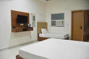 a hotel room with two beds and a tv at The Ora Hotel in Vrindāvan