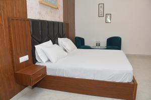 a bedroom with a bed and two blue chairs at The Ora Hotel in Vrindāvan