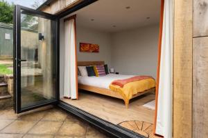 a bedroom with a bed in a room with sliding glass doors at Cotswolds Cabin in Stonesfield