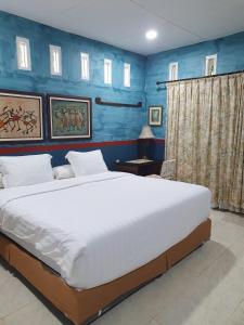 a bedroom with a large bed with blue walls at Ruma Kaca Simanindo Bed&Breakfast in Panjaitan