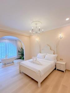 a white bedroom with a bed and a bath tub at The Cozy Cottage Semporna in Semporna