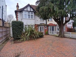 a house with a tree and a brick driveway at Osterley Studio Room in Isleworth
