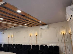 ein Raum mit weißen Wänden, schwarzen Stühlen und Lampen in der Unterkunft Hotel La Opera in Gwalior