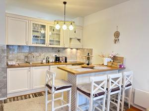 a kitchen with white cabinets and a counter with stools at Planinski MIR Bjelašnica in Bjelašnica