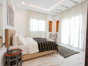 a bedroom with a bed and a chair and windows at Villa Africa in Essaouira