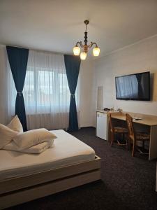 a hotel room with a bed and a desk and a television at Pension Regal in Satu Mare +71 photos