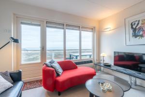 a living room with a red chair and a table at Appartementencomplex Juliana 152 in De Koog