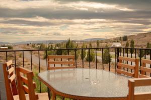a glass table and chairs on a balcony with a view at Hosteria Casa kuyen in El Calafate