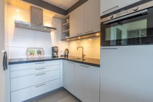 a kitchen with white cabinets and a sink at Appartementencomplex Juliana 152 in De Koog