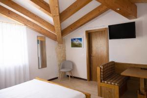 a bedroom with a bed and a chair and a television at Hotel Rododendro Val di Fassa in Campitello di Fassa