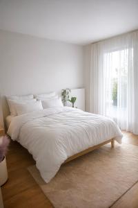 a white bedroom with a large bed and a window at Penthouse 166 m2- Terrasse & Parking - Paris Sud - Orly - Parc Expo in Bagneux