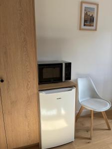 a microwave on top of a refrigerator next to a white chair at Studio moderne Arcueil in Arcueil