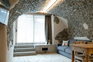 a living room with a blue couch and a stone wall at Grotta Bàlzer in Valdidentro