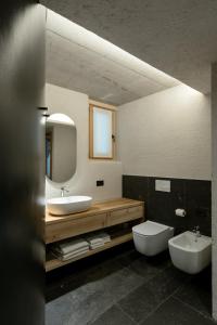 a bathroom with a sink and a toilet and a mirror at Grotta Bàlzer in Valdidentro