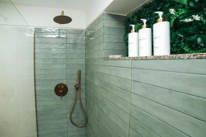 a shower with a hose in a bathroom with green tiles at Magníficos Dias Atlânticos Studio in Moledo +24 photos