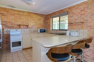 a kitchen with a white counter and a brick wall at Pamusha 2 in Geraldton
