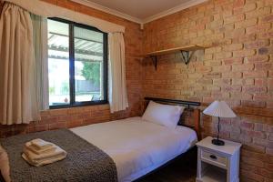 a bedroom with a bed and a brick wall at Pamusha 2 in Geraldton