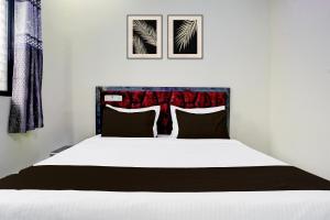 a bedroom with a white bed with two pictures on the wall at SPOT O SKY LINE in Chandrapur