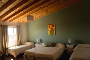a bedroom with two beds and a ceiling with beams at Hosteria Casa kuyen in El Calafate