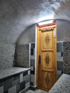 a wooden door in a room with a stone wall at Riad Golden Baibah in Zaouia Akermoud