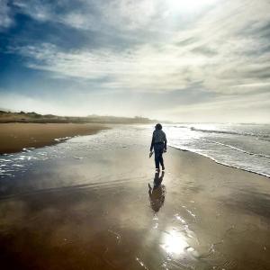 a man walking on the beach near the water at Riad Golden Baibah in Zaouia Akermoud