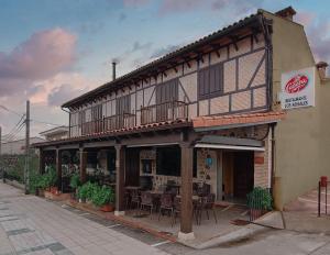 a building with a table and chairs in front of it at Hostal Los Rosales in Tejeda de Tiétar