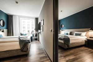 a hotel room with two beds and a mirror at HARBR Hotel Konstanz, a member of Radisson Individuals in Konstanz
