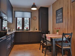 a kitchen with a table and chairs and a kitchen with a sink at Dworek Brzozowy, Augustów Płaska in Płaska