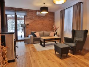a living room with a couch and chairs and a brick wall at Dworek Brzozowy, Augustów Płaska in Płaska