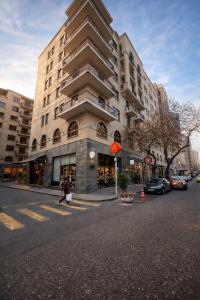 a person crossing a street in front of a tall building at Republic Square In Hotel California in Yerevan