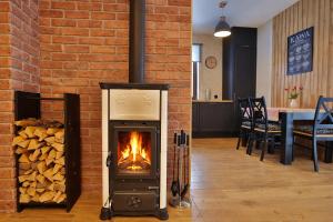 a wood stove in a room next to a brick wall at Dworek Brzozowy, Augustów Płaska in Płaska