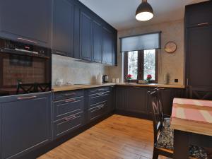 a kitchen with dark blue cabinets and a table at Dworek Brzozowy, Augustów Płaska in Płaska +28 photos