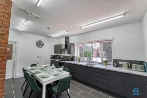 a kitchen with a table with green chairs and a counter at 4 Bedrooms- Sleeps 8 in Kidderminster