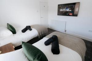 a room with two beds and a tv on the wall at Meldon Cottage with Private Hot Tub in Newbiggin-by-the-Sea