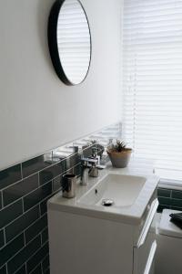 a bathroom with a white sink and a mirror at Meldon Cottage with Private Hot Tub in Newbiggin-by-the-Sea +16 photos