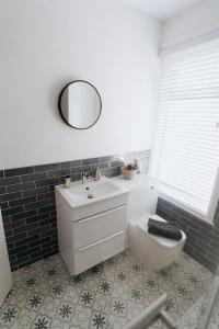 a bathroom with a sink and a toilet and a mirror at Meldon Cottage with Private Hot Tub in Newbiggin-by-the-Sea
