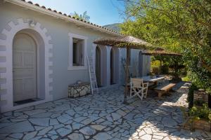 a patio of a house with a table and an umbrella at Stavlos Cottage in Vasiliki
